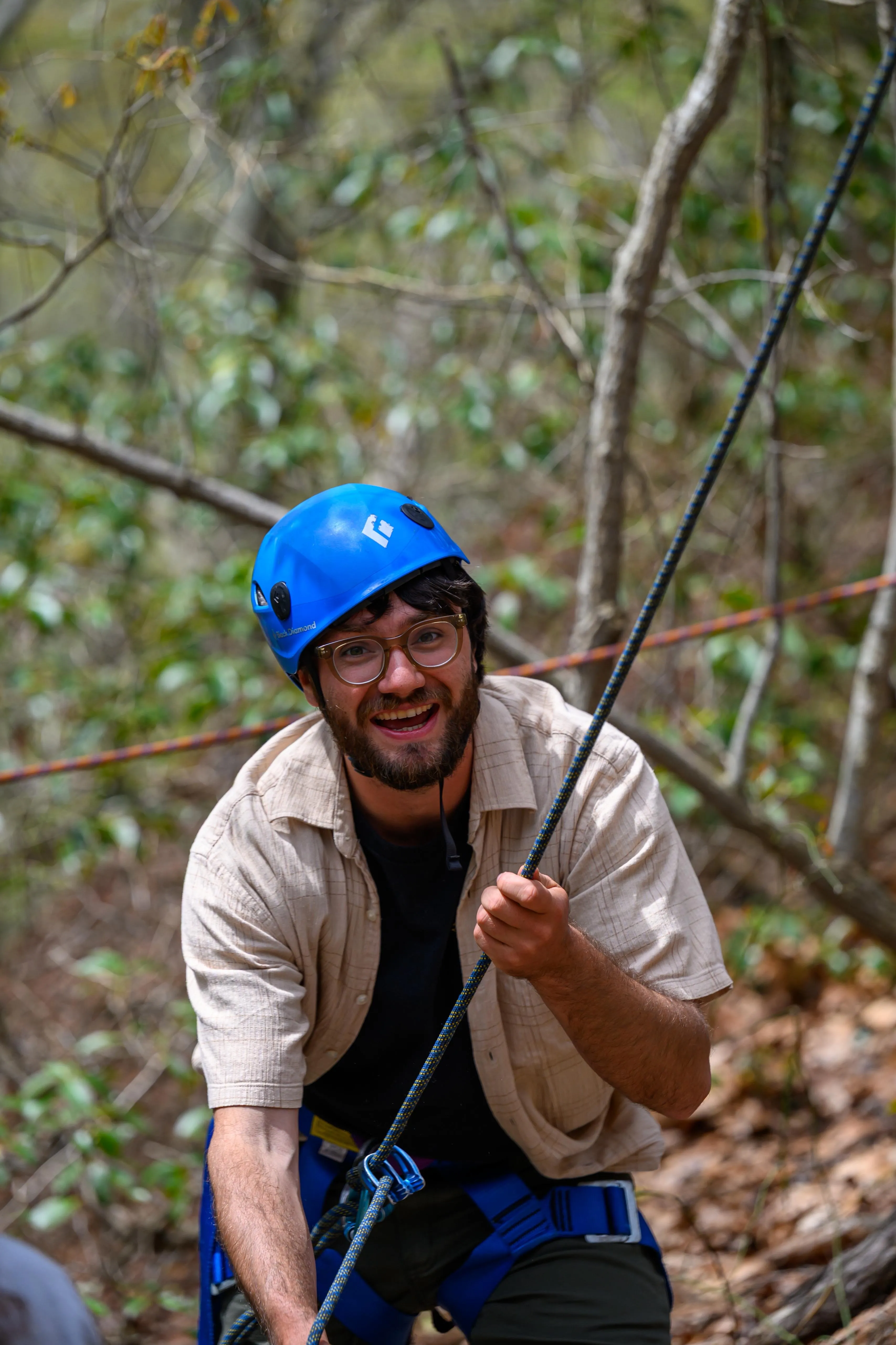 Eric mid-belaying in a blue climbing helmet, grinning